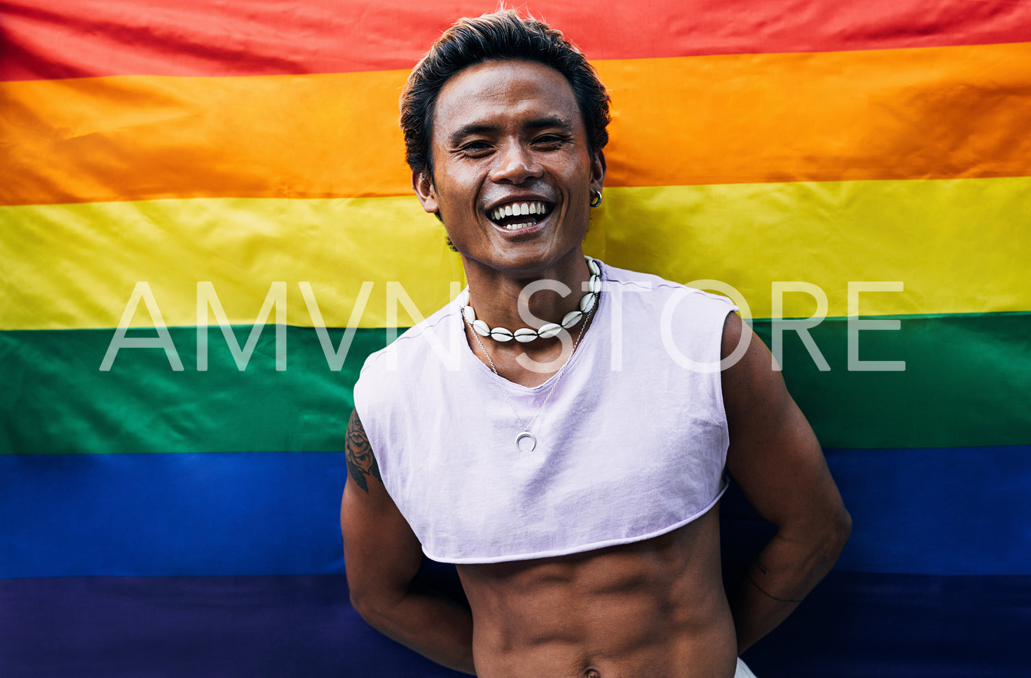 Happy guy posing on LGBT flag. Laughing male standing against rainbow flag.