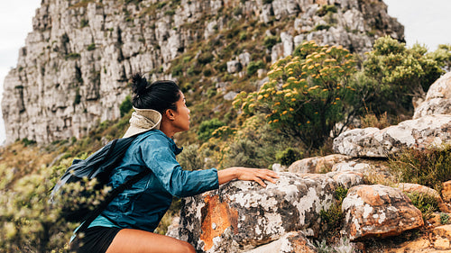 Woman hiker climbing up on a mountain. Young female hiking over extreme terrain.