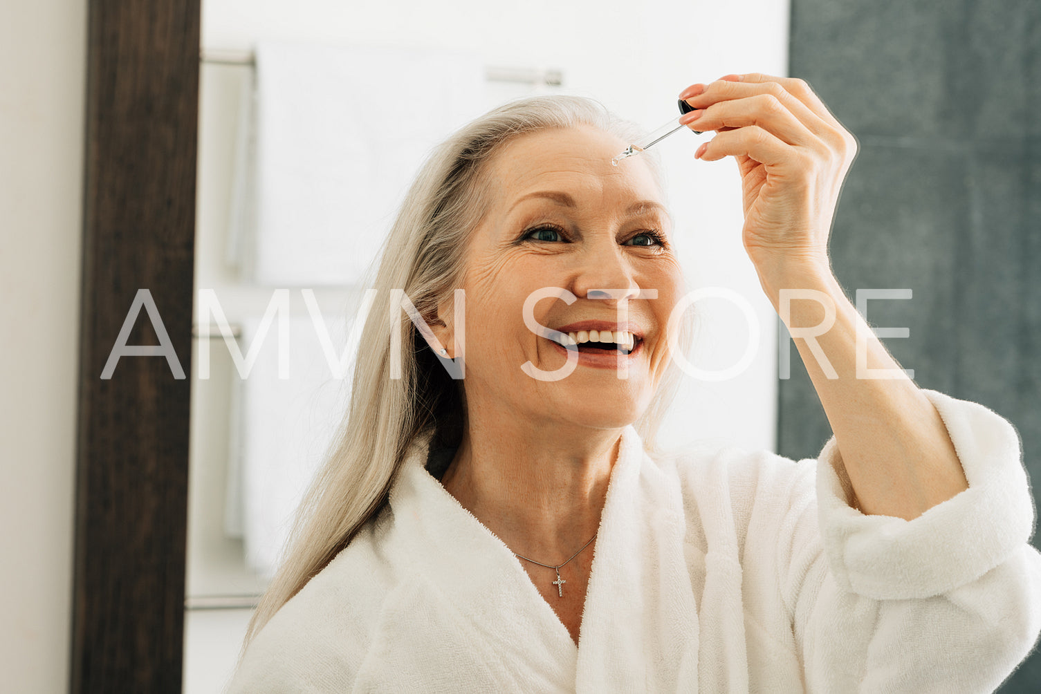 Smiling senior woman holding pipette with hyaluronic acid. Happy female applying liquid facial treatment.