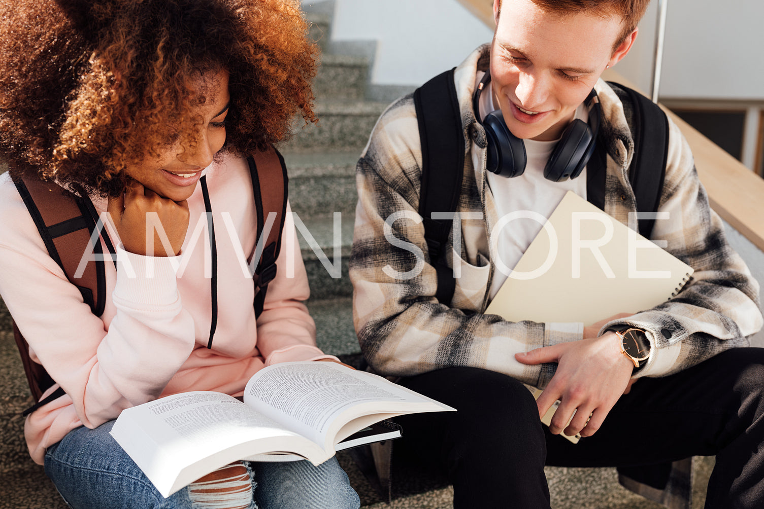 College students reading a book while sitting on a stairs