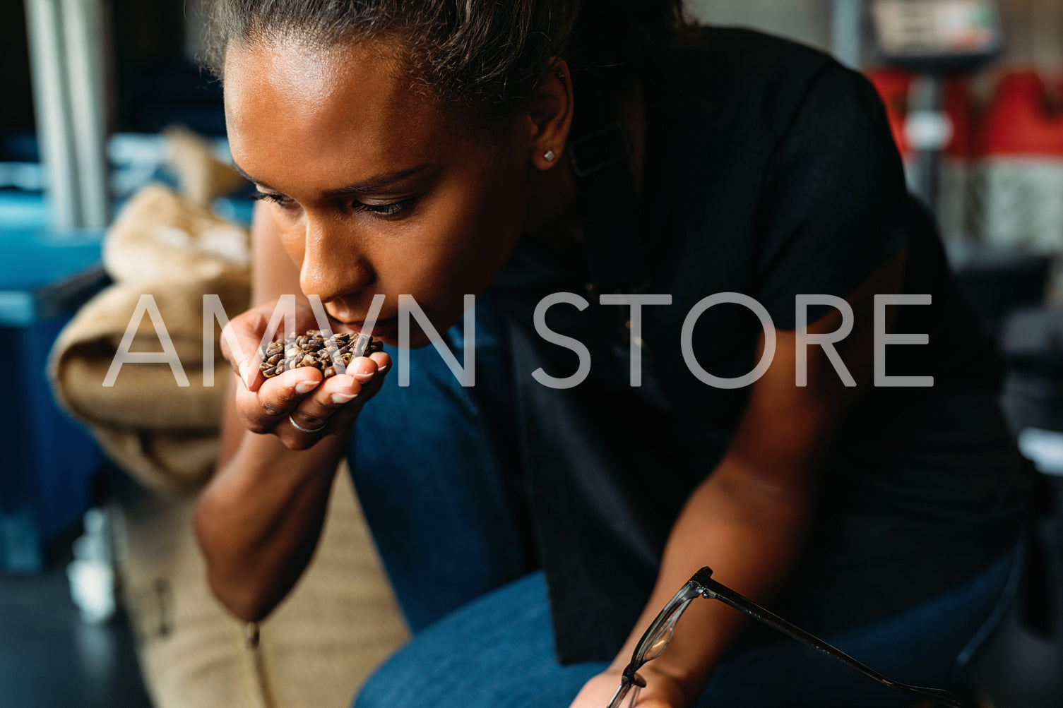 Woman examining and smelling the aroma of coffee beans after roasting	