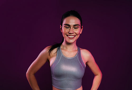 Portrait of a cheerful sportswoman
in silver fitness wear against a magenta backdrop