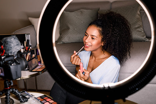 Woman recording makeup tutorial with dslr and ring light