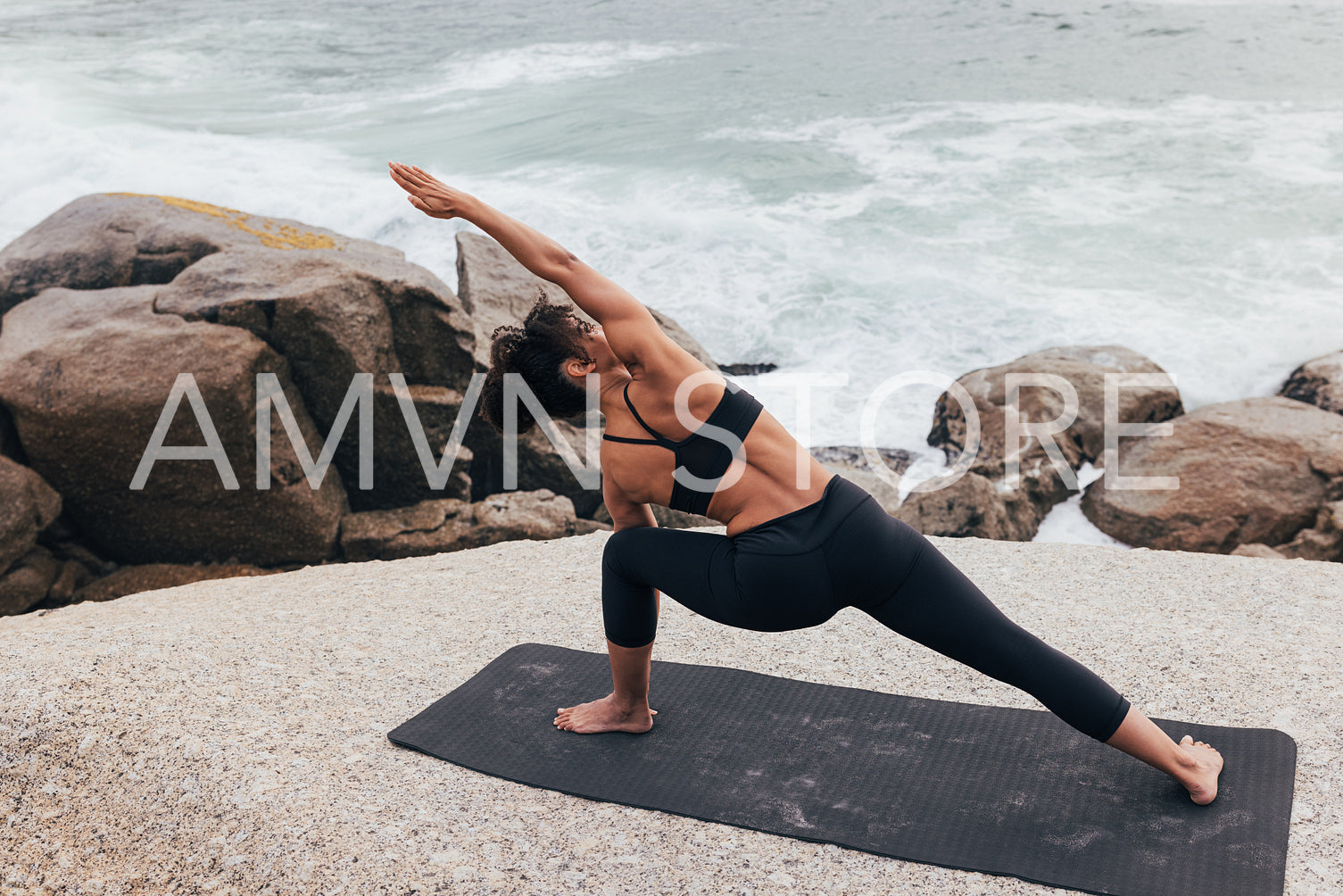 Woman stretching her body on mat by ocean. Female practicing yoga outdoors at seaside.