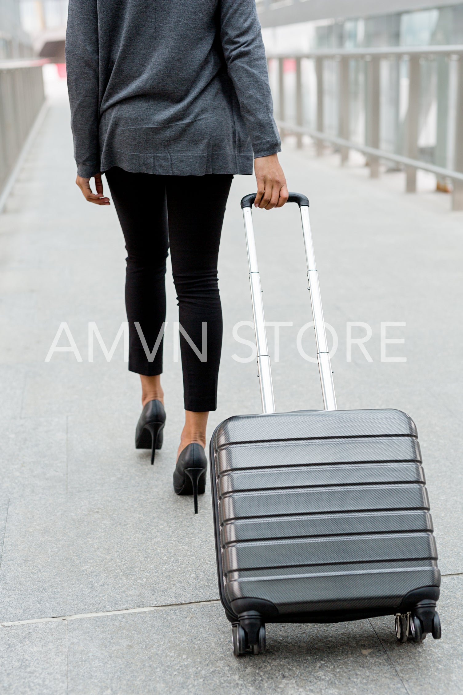 Unrecognizable businesswoman pulling suitcase inside of airport terminal	