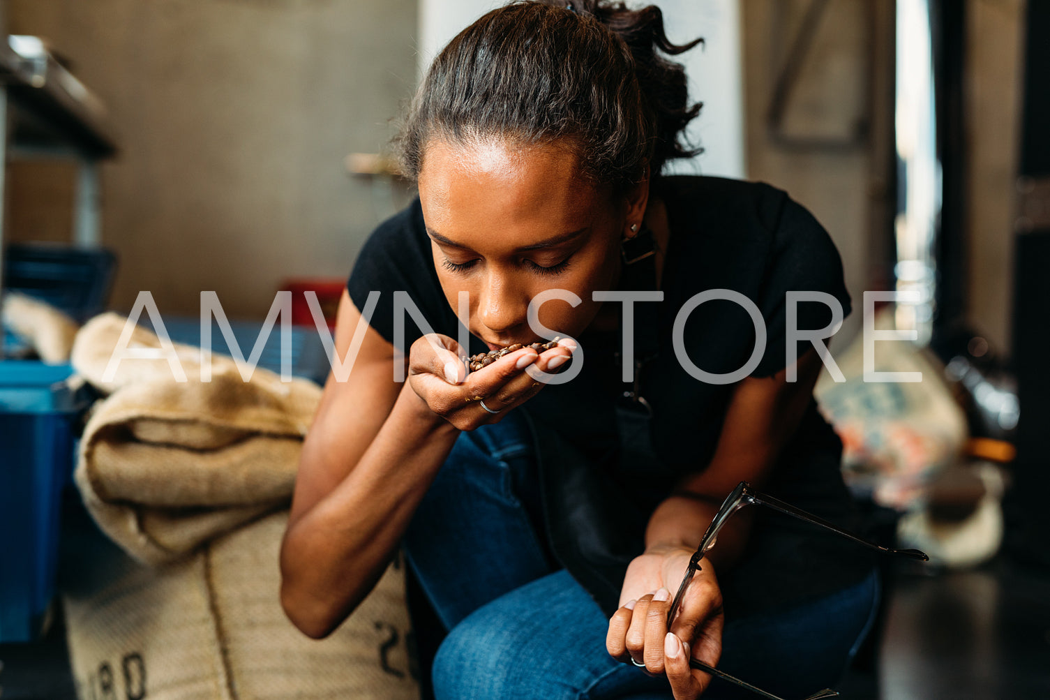 Barista smelling fresh roasted coffee beans in her coffee shop	