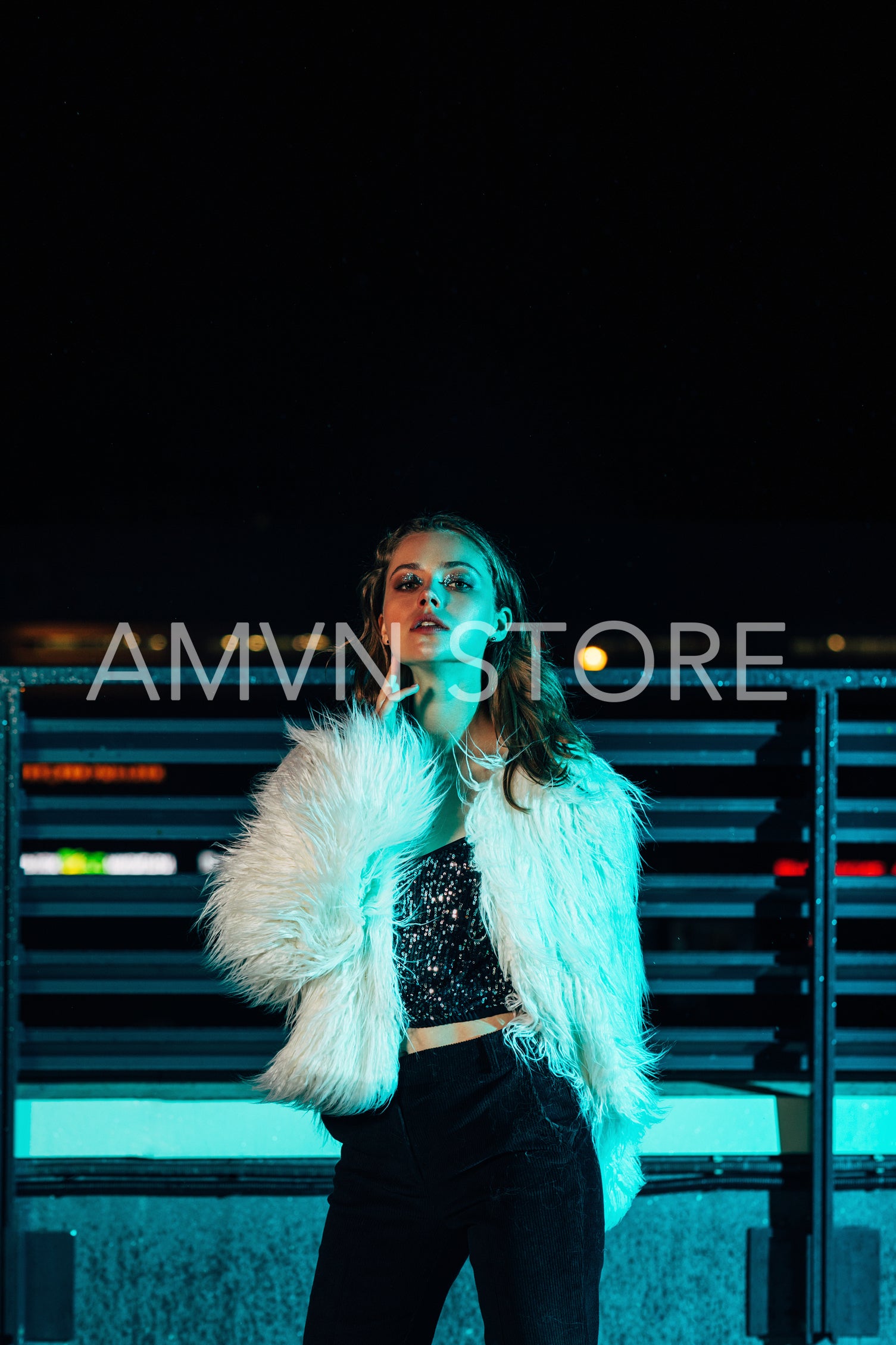 Young beautiful woman wearing white fur coat standing outdoors at night	