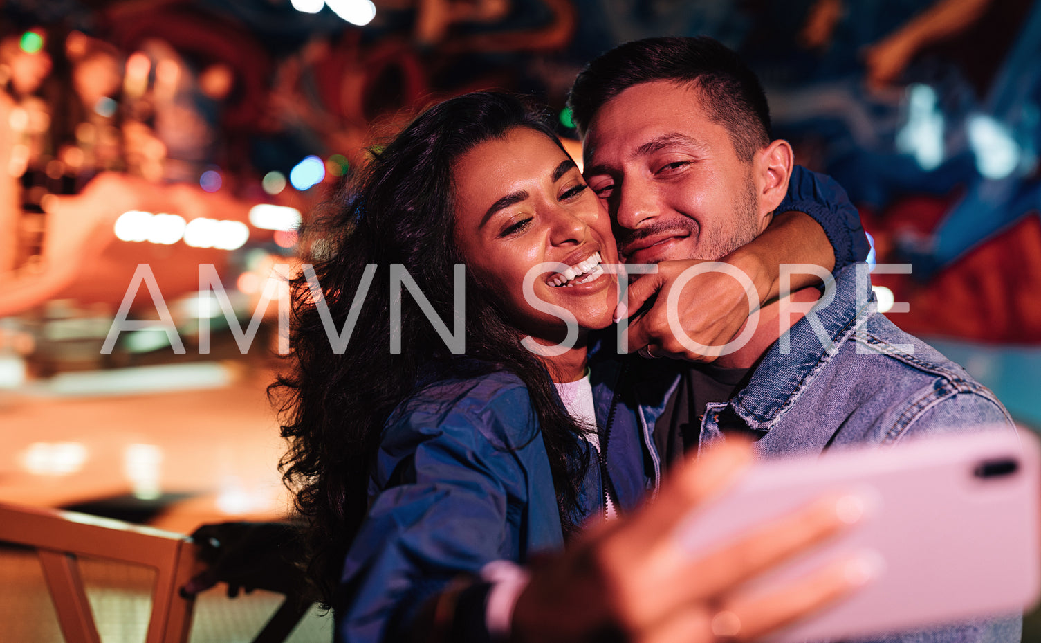 Laughing couple taking selfie and having fun in amusement park. Happy man and woman enjoying the summer festival.