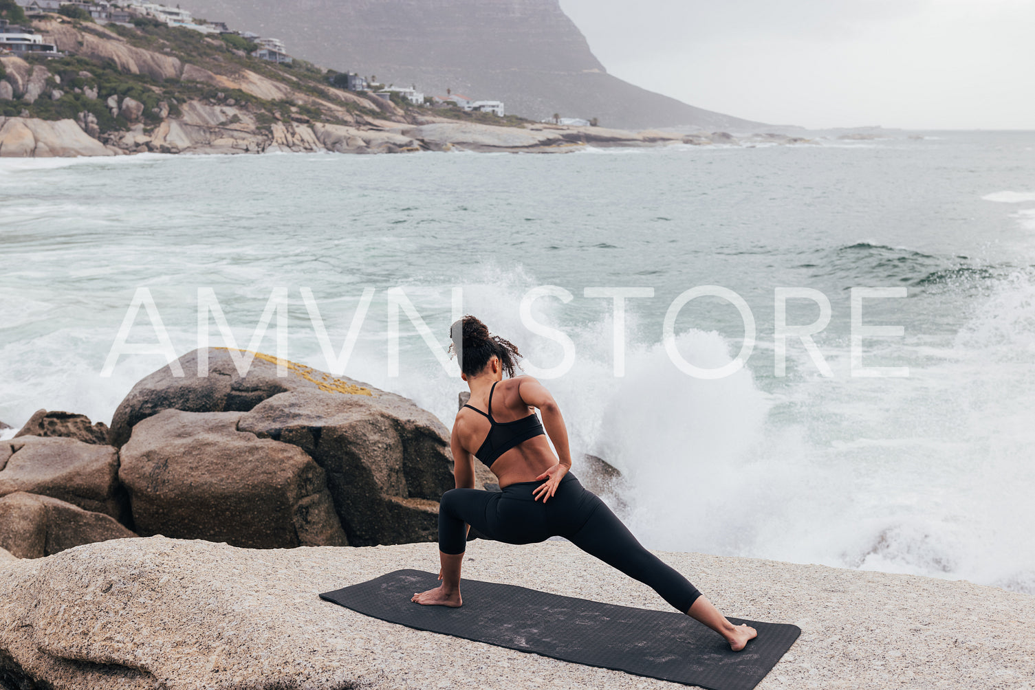 Fitness woman doing stretching exercises on a mat against waves and ocean at sunset