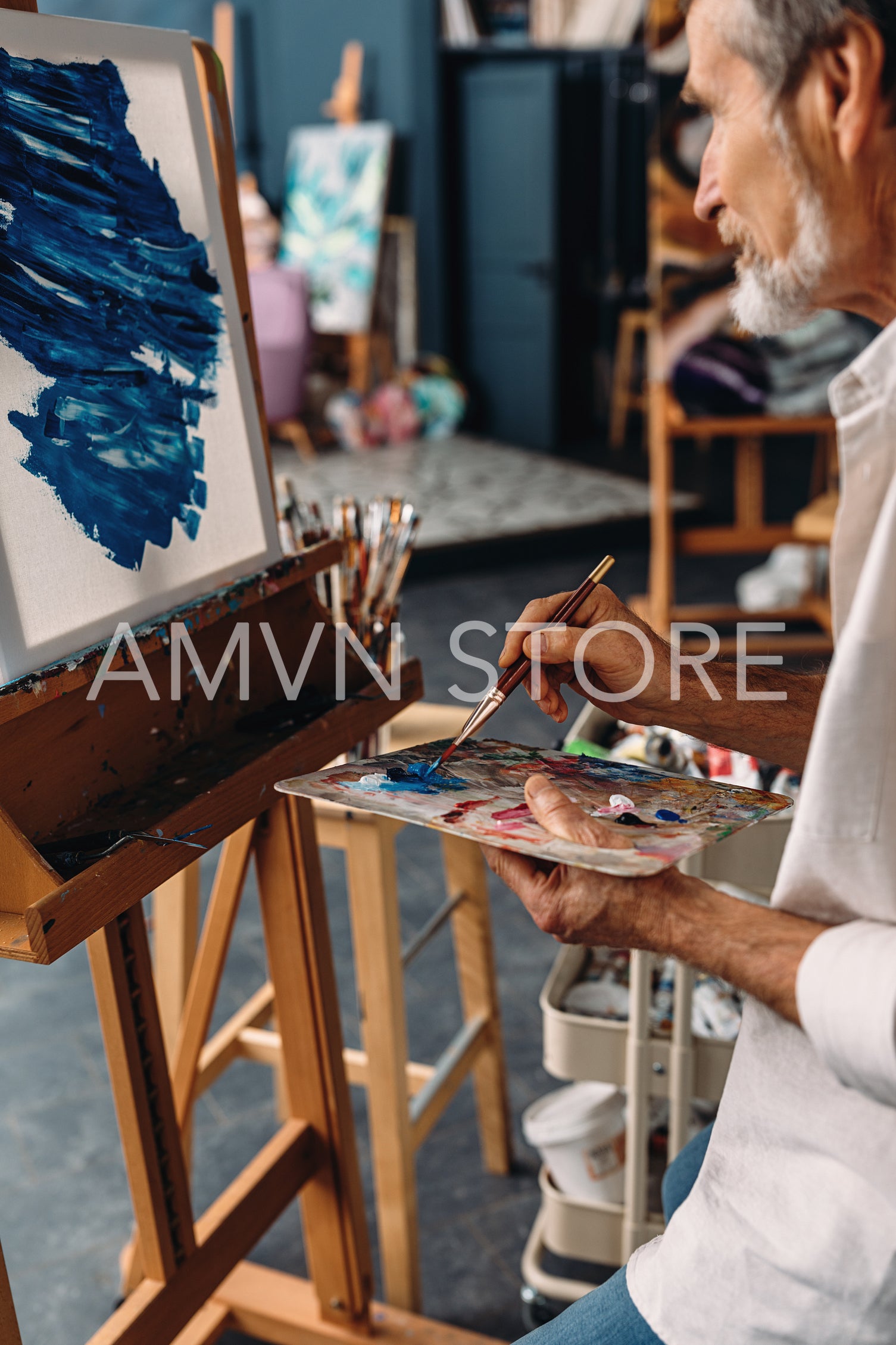 Senior artist working in studio. Painter holding a palette and drawing on canvas.	