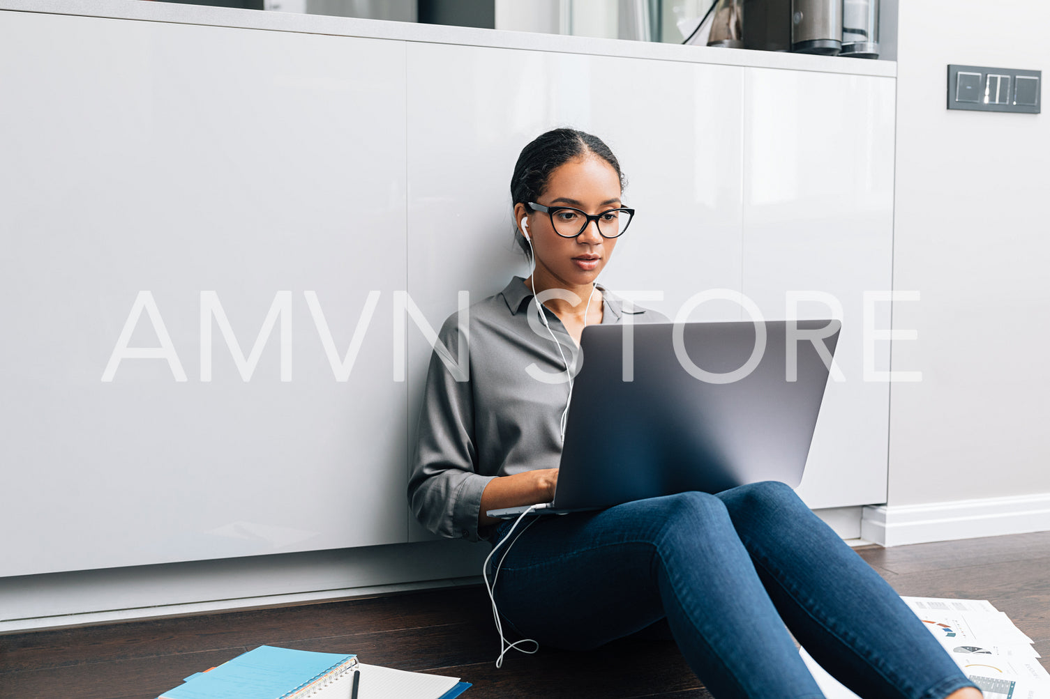 Young woman working from home. Female entrepreneur sitting on floor and using laptop computer.	