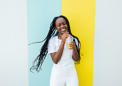 Happy girl in white clothes holding a cocktail and having fun while standing outdoors