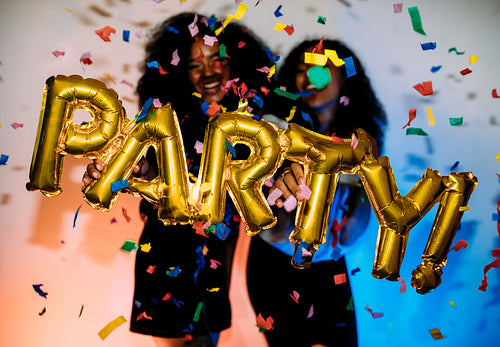 Happy girls standing near a wall under confetti