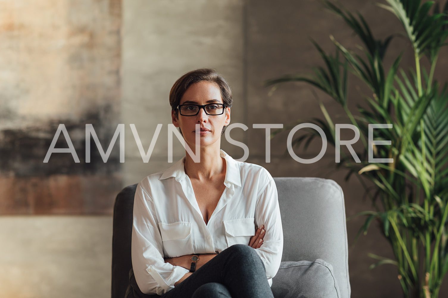 Confident female sitting in her loft. Businesswoman in eyeglasses and formal wear.