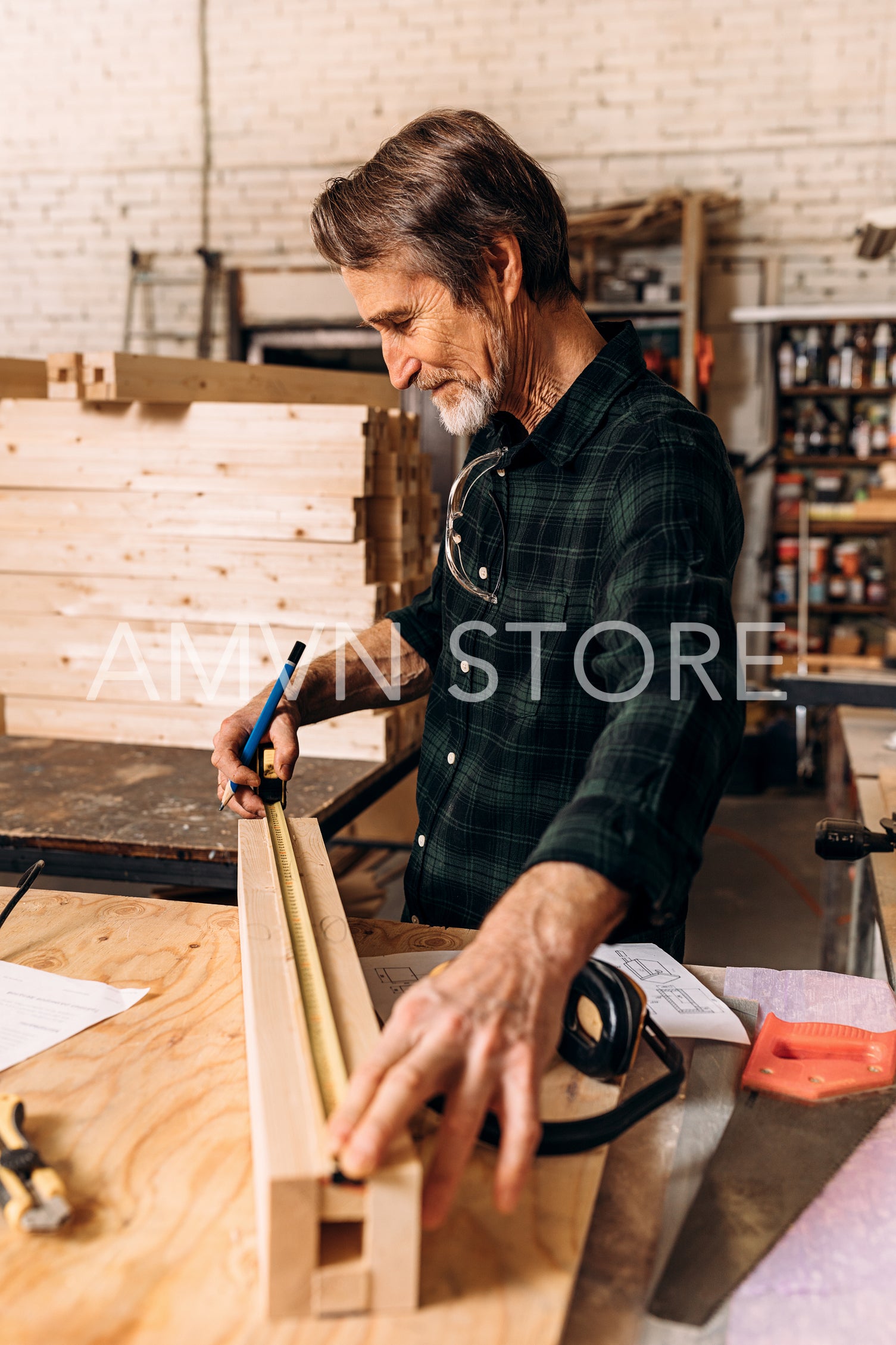 Side view of senior carpenter doing markings on a wooden bar with using a measuring tape	