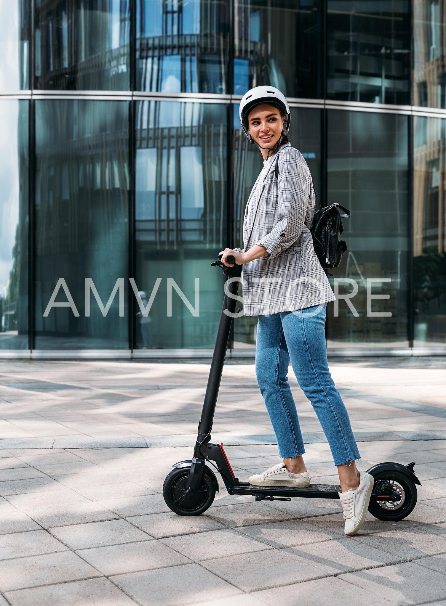 Stylish cheerful woman standing on electric push scooter and looking away 