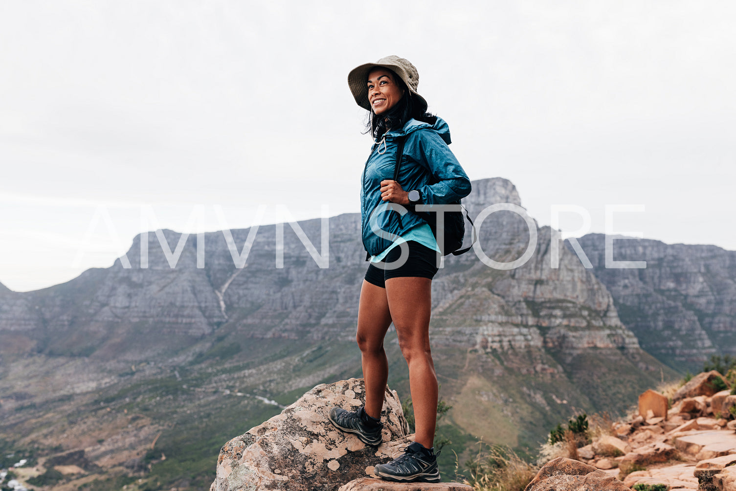 Young woman in sports clothes and hat enjoying the view during a hike