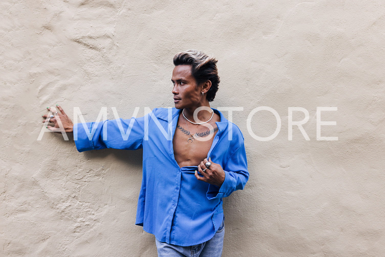 Young stylish guy in a blue shirt standing at wall outdoors