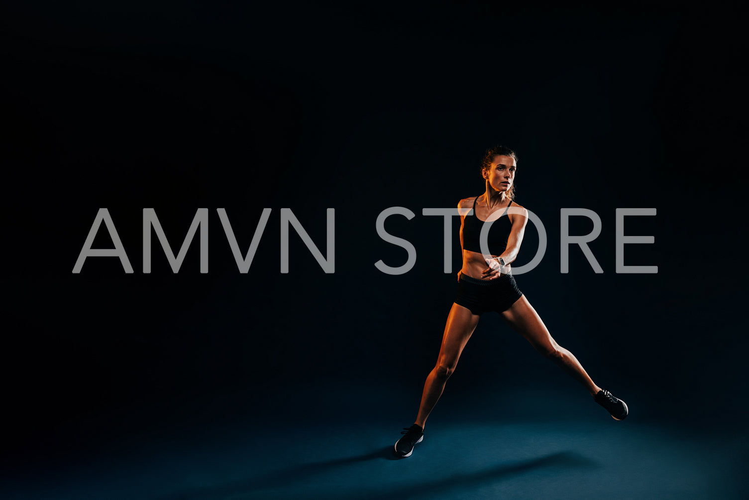 Healthy strong woman jumping from side to side on black background warming up