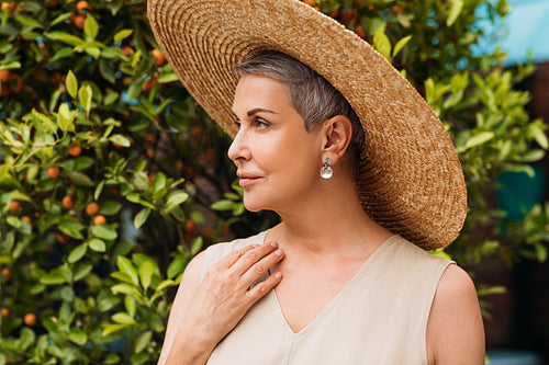 Side view of an aged female in straw hat in the park