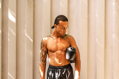 Tired boxer standing with gloves at the wall looking down