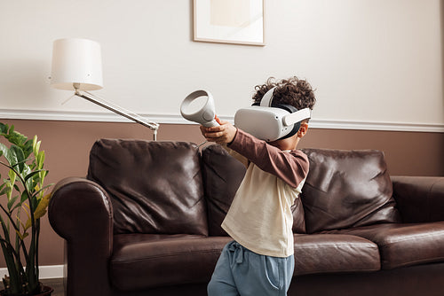 Kid playing virtual reality game in a living room holding joysti