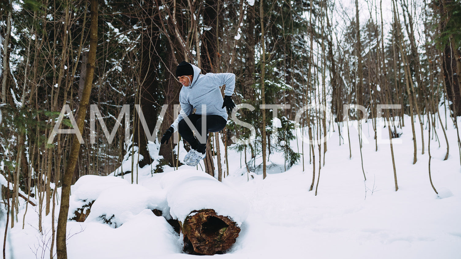 Young sportsman jumping through a tree in snowy forest	
