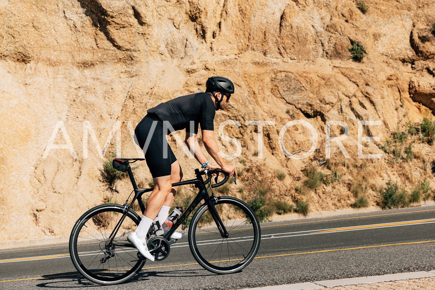 Cyclist in black sportswear doing intense training outdoors. Side view of a triathlete on a bicycle.