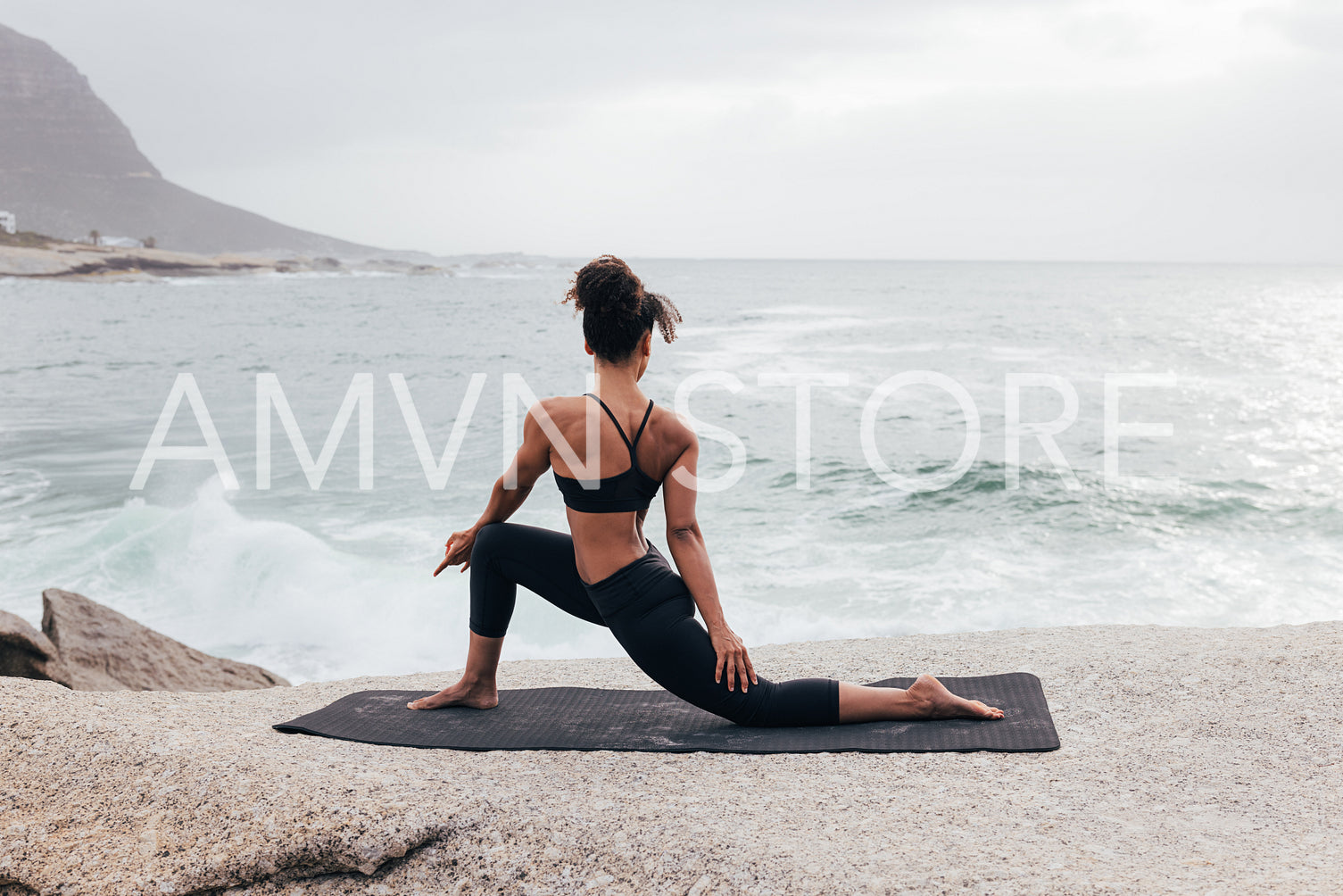 Young woman practicing yoga at evening by ocean. Slim female stretching her body by coast.