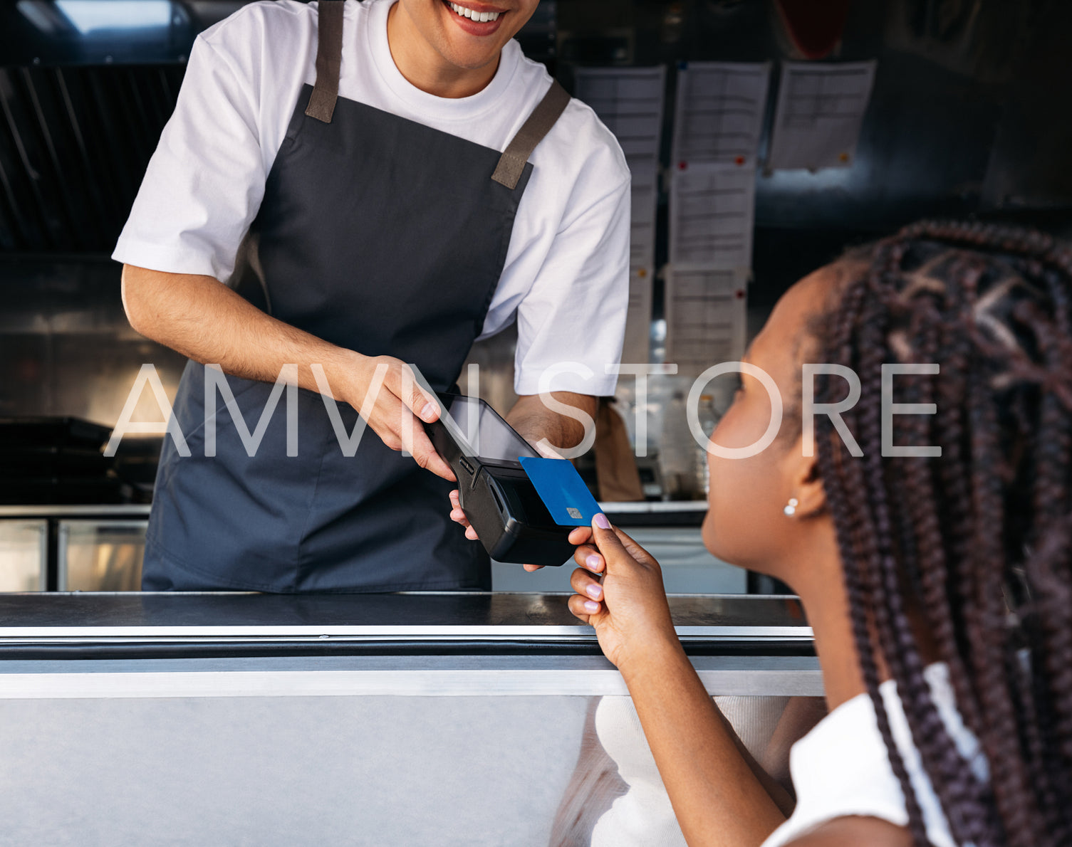 Cropped shot of a food truck owner holding a POS terminal while a female customer pays by a contactless card