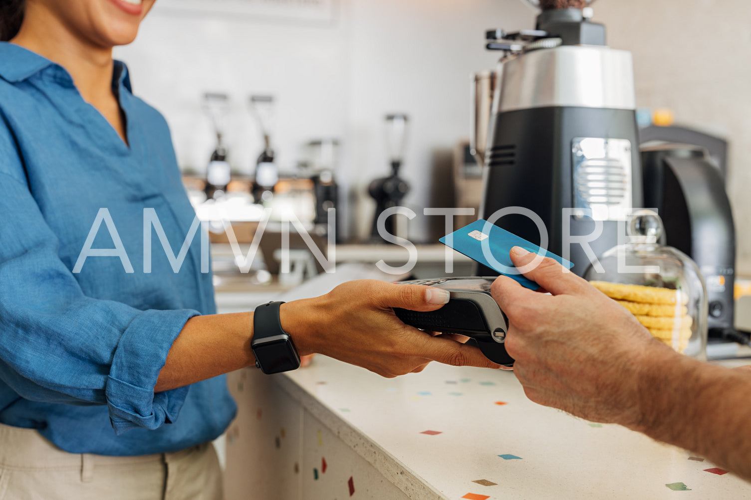 Unrecognizable female employee taking payment from customer in coffee shop. Hand of a customer making contactless payment using credit card.	