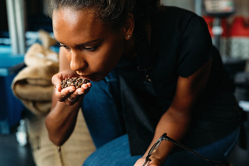 Woman examining and smelling the aroma of coffee beans after roasting