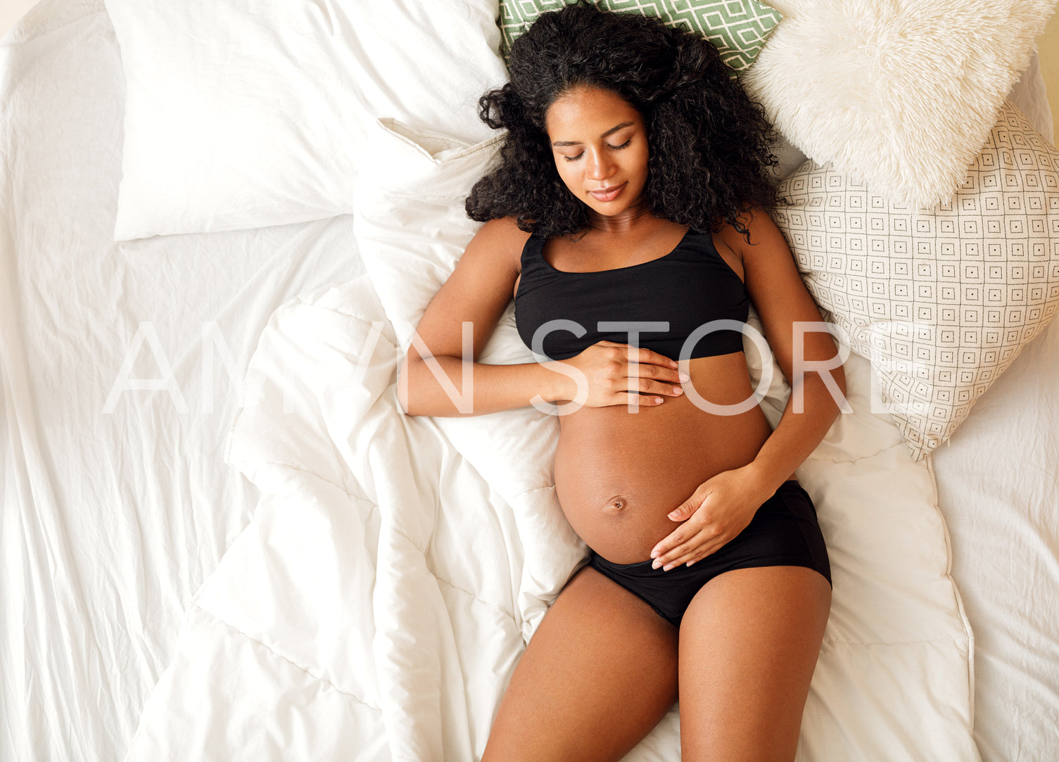 High angle view of young pregnant woman on a bed