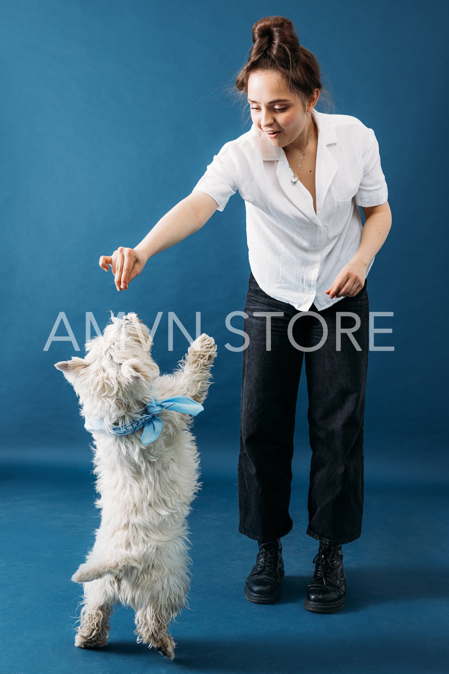 Young woman in casuals feeding her little dog with white fur in 