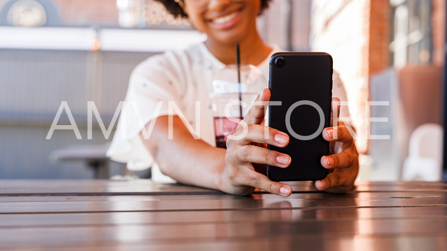 Close up of woman hands holding a smartphone. Young blogger taking selfie with a drink on table.	