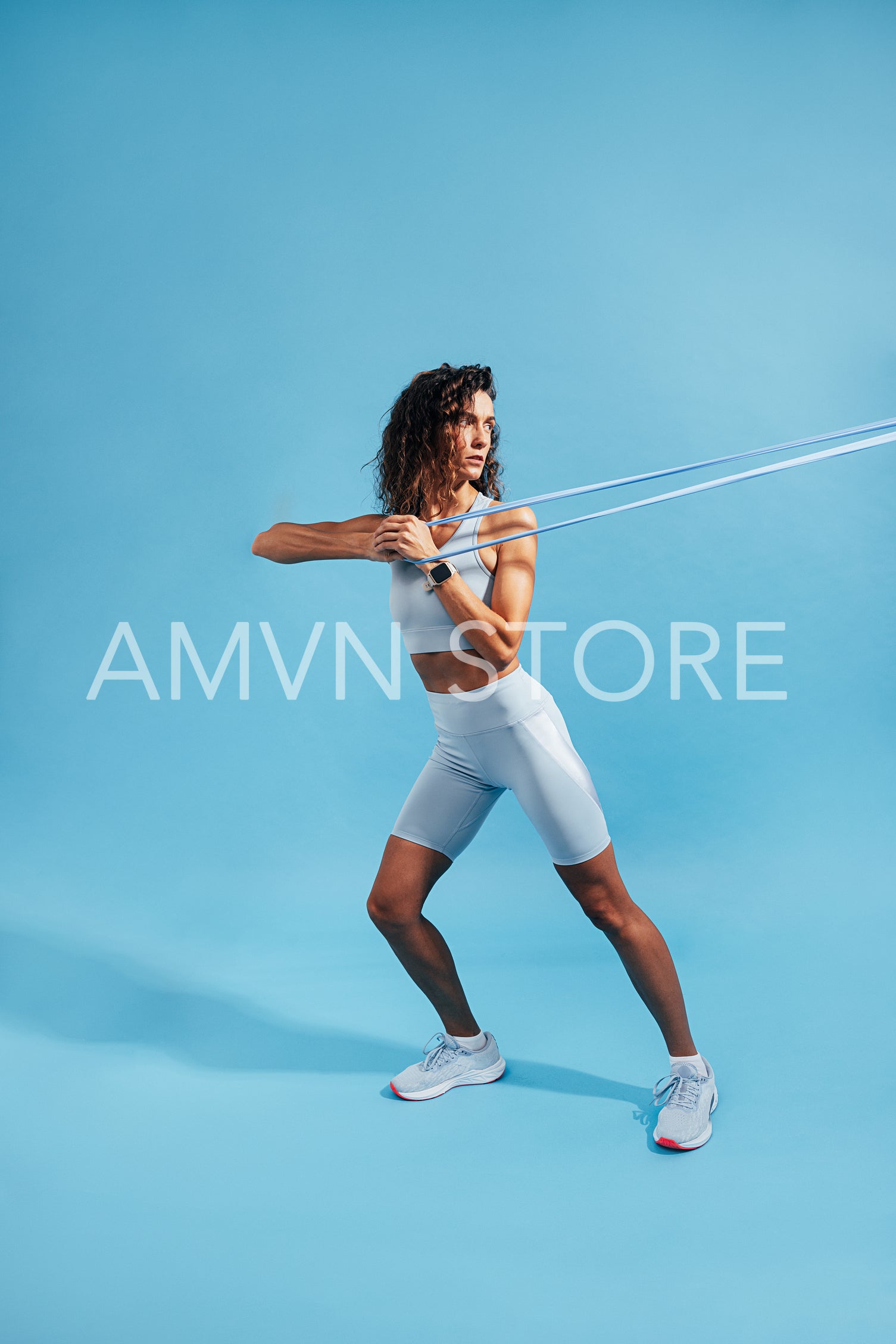 Woman doing intense core strength training using resistance band on blue background