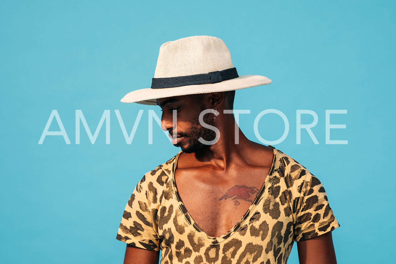 Portrait of a stylish man in hat posing against blue background looking sideways