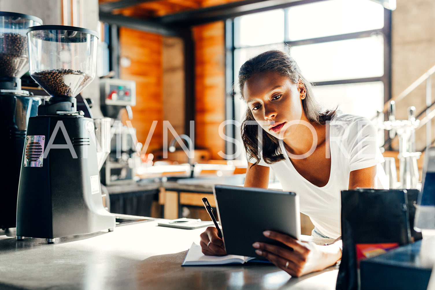 Cafe owner leaning on counter making notes in cafe	