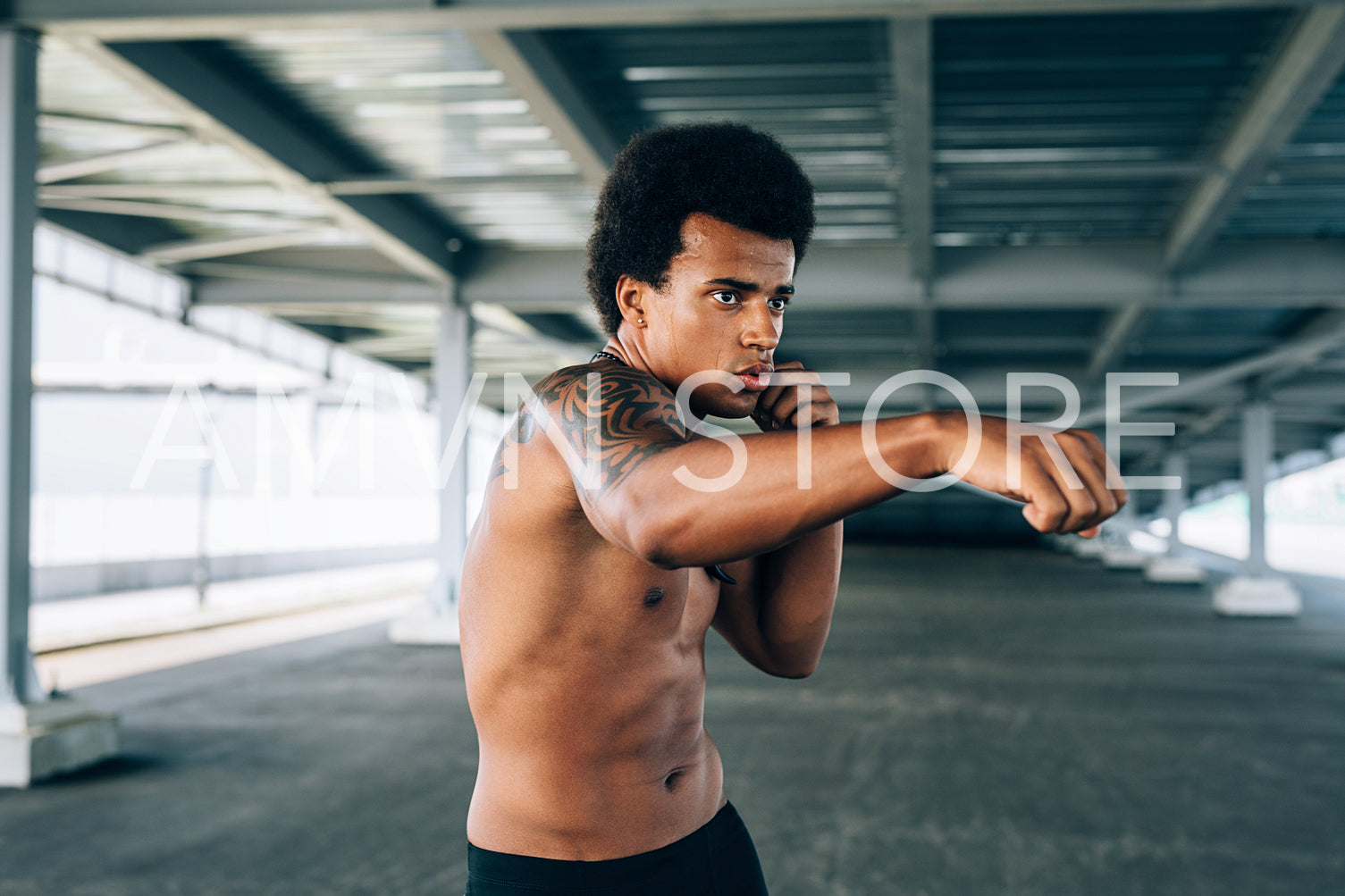 Young bare chested kickboxer doing shadow boxing, practicing his punches outdoors	