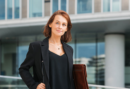 Smiling middle-aged businesswoman walking against office building. Portrait of a middle-aged female in formal wear.