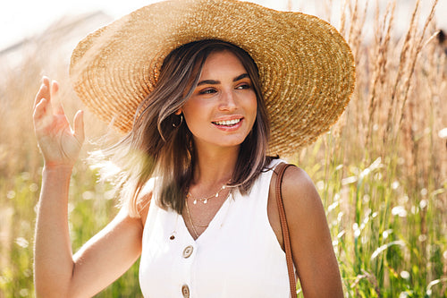 Young happy woman wearing big straw hat standing on the field