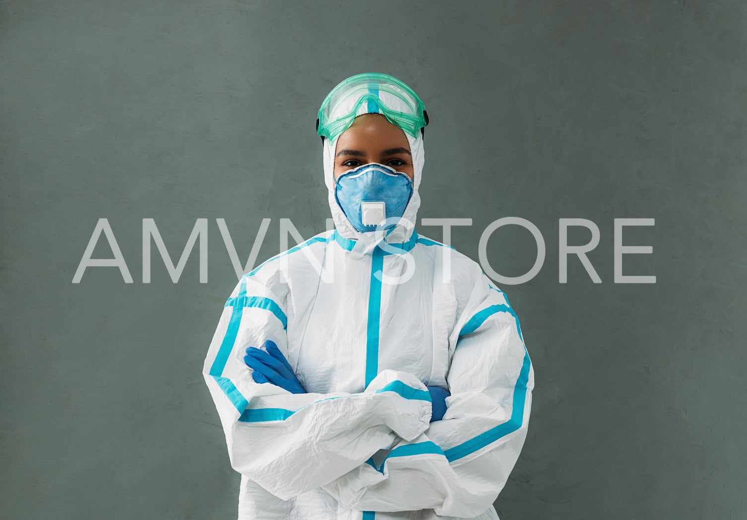 Portrait of a confident medical specialist wearing a protective suit, mask and glasses standing at wall