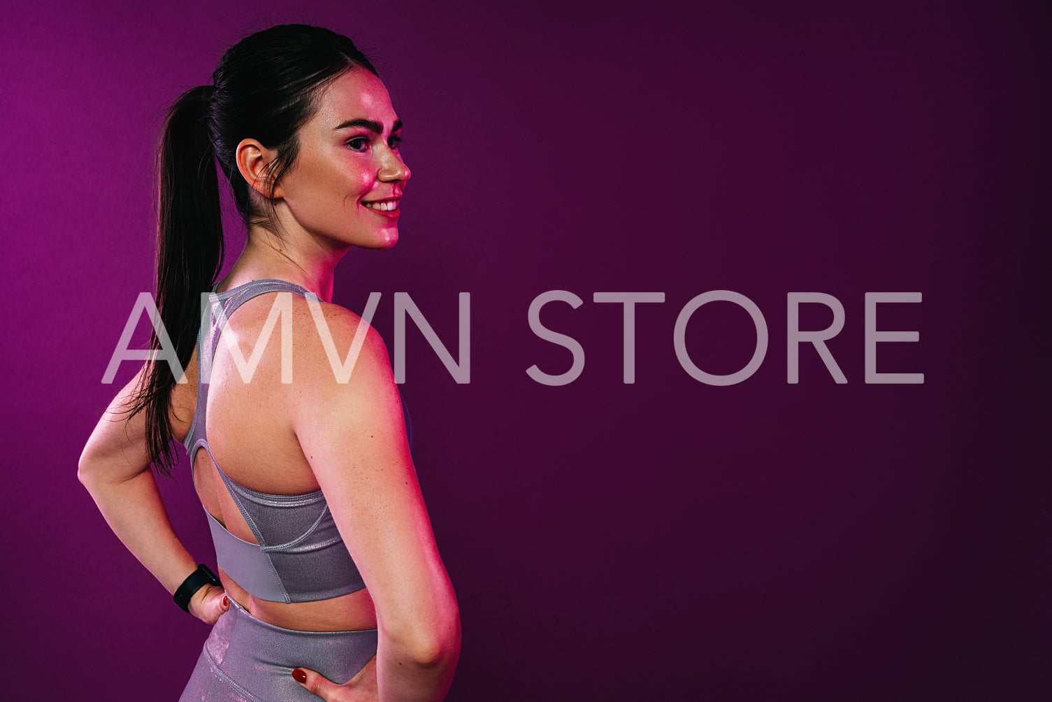 Rear view of young cheerful sportswoman looking away standing in studio at magenta background