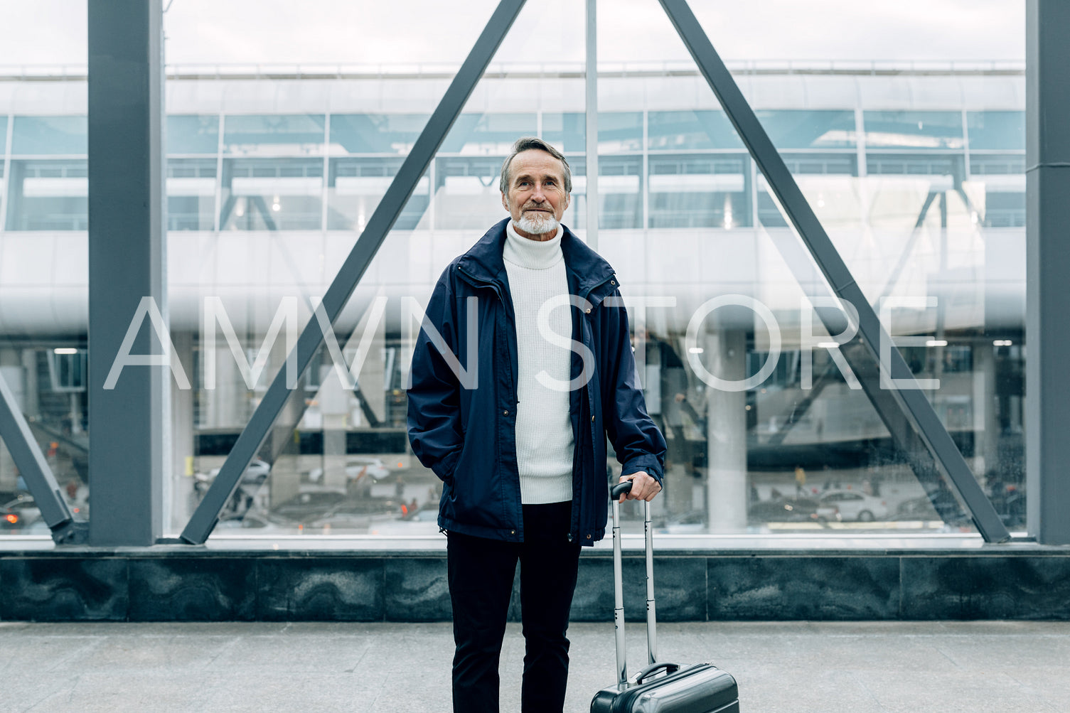 Handsome mature traveler standing with his suitcase in airport terminal	