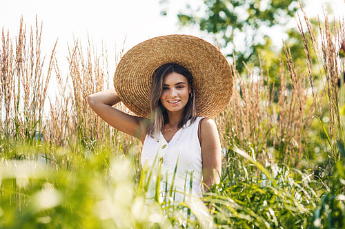 Young cheerful woman wearing big straw hat and looking at camera