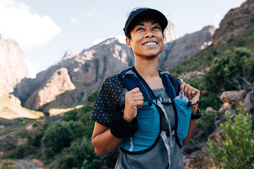 Portrait of positive woman hiker standing in valley. Young female enjoying the hike.