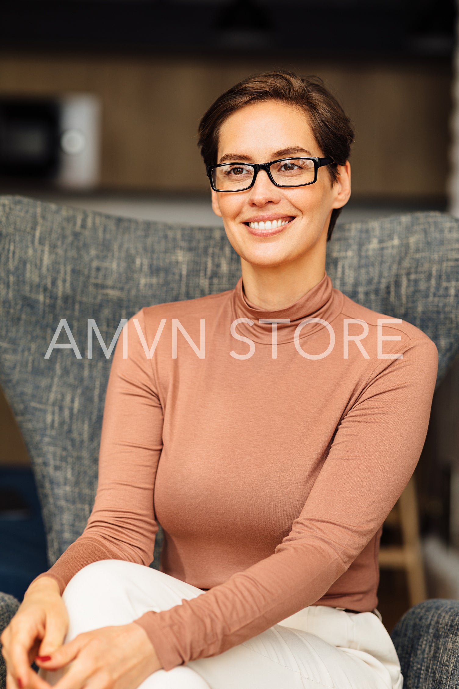 Portrait of a smiling entrepreneur in glasses sitting on armchair	