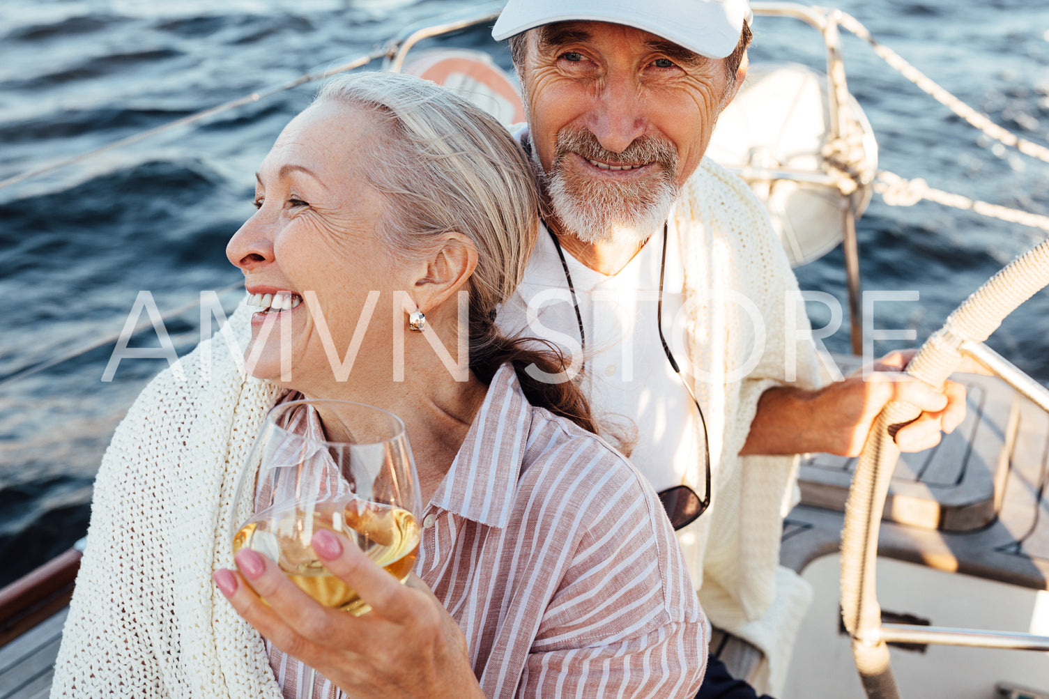 Woman on yacht uses a hat to hide her face from the sun	