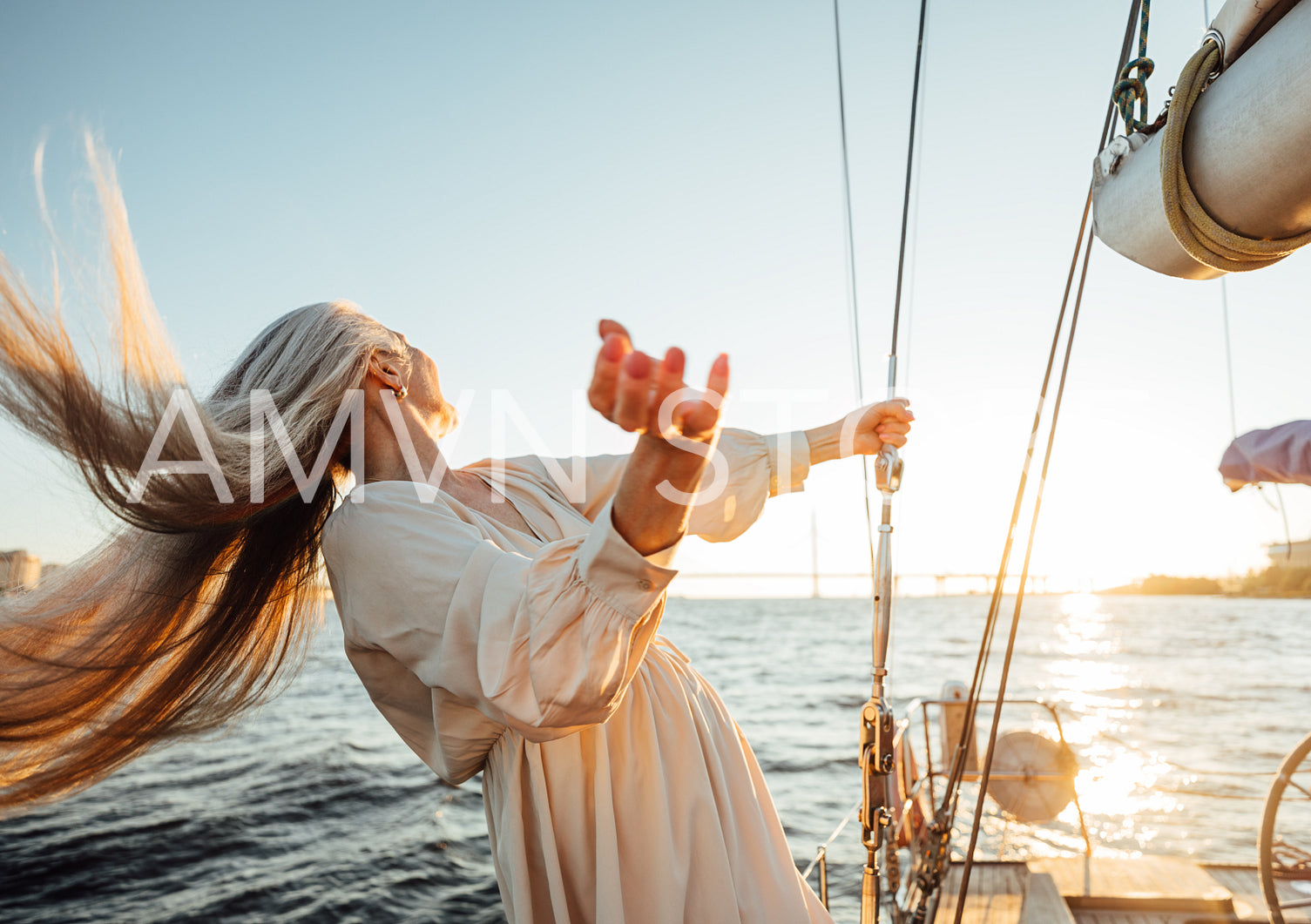 Unrecognizable mature woman with long hair having fun on a yacht and looking on sunset	