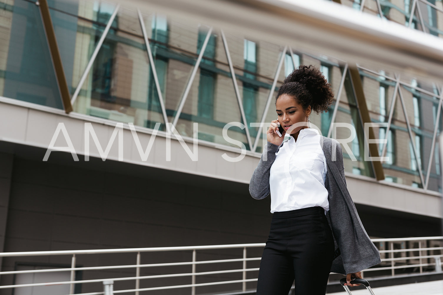 Beautiful woman talking on cellphone while walking at building	